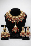Royal Kundan bridal jewellery set featuring gold-tone necklace, jhumka earrings and maang tikka with ruby red stones and pearl drops