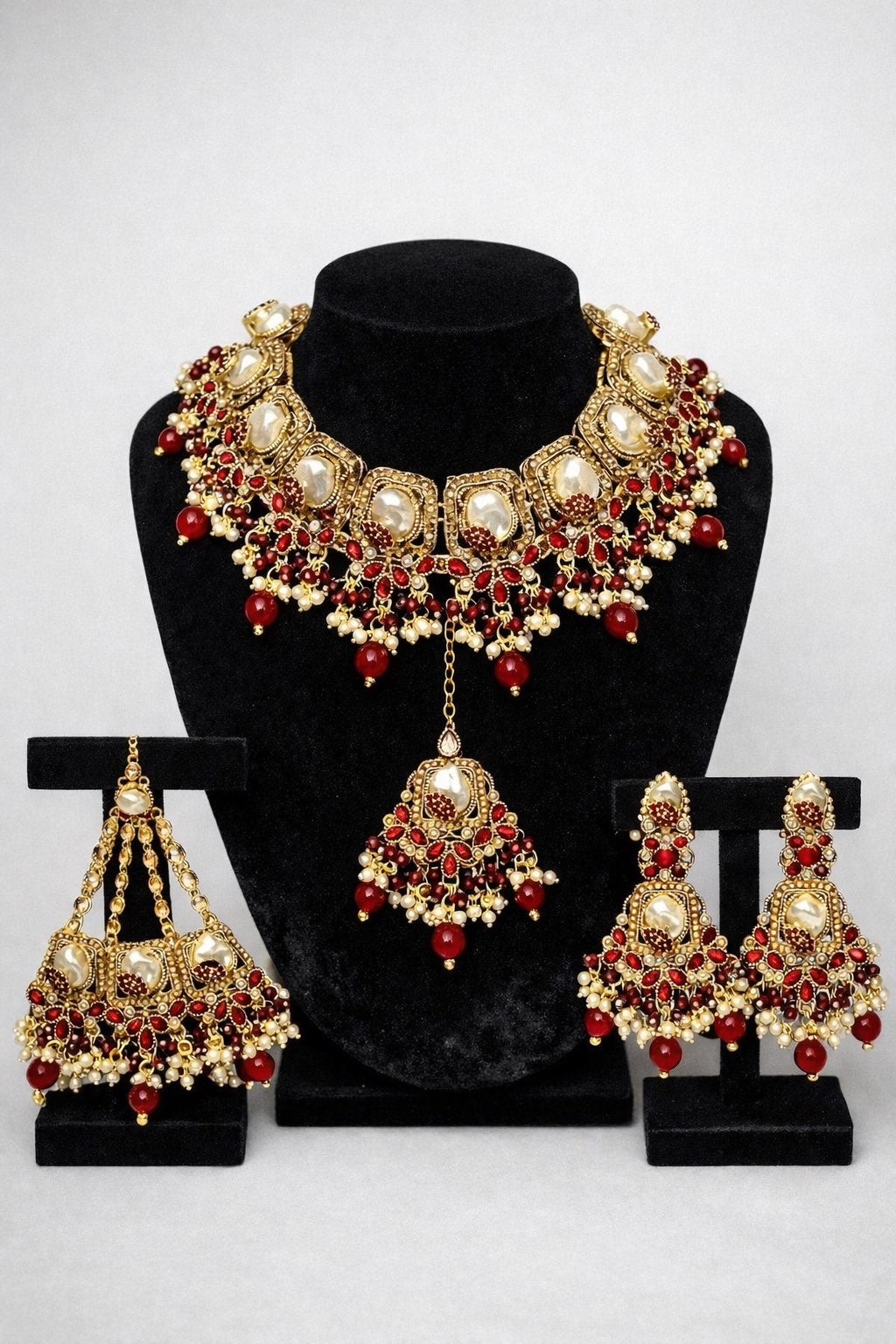 Royal Kundan bridal jewellery set featuring gold-tone necklace, jhumka earrings and maang tikka with ruby red stones and pearl drops