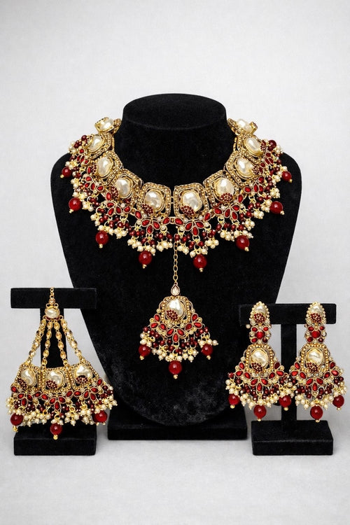 Royal Kundan bridal jewellery set featuring gold-tone necklace, jhumka earrings and maang tikka with ruby red stones and pearl drops